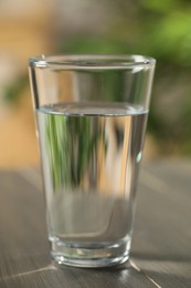 Photo of Glass of pure water on wooden table against blurred background, closeup