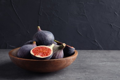 Photo of Bowl with fresh ripe figs on gray table. Space for text