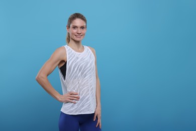 Photo of Portrait of happy sportswoman on light blue background, space for text