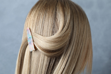 Photo of Young woman with beautiful hair clip on blue background, closeup