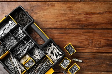 Photo of Organizer with many different fasteners and wrenches on wooden table, flat lay. Space for text