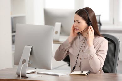 Photo of Confused hotline operator with headset working on computer in office