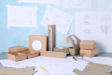 Photo of Creating packaging design. Drawings, boxes and stationery on table, closeup