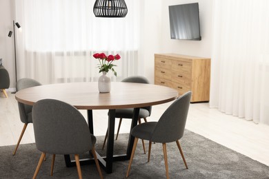 Photo of Chairs and table with vase of red rose flowers in dining room. Stylish interior