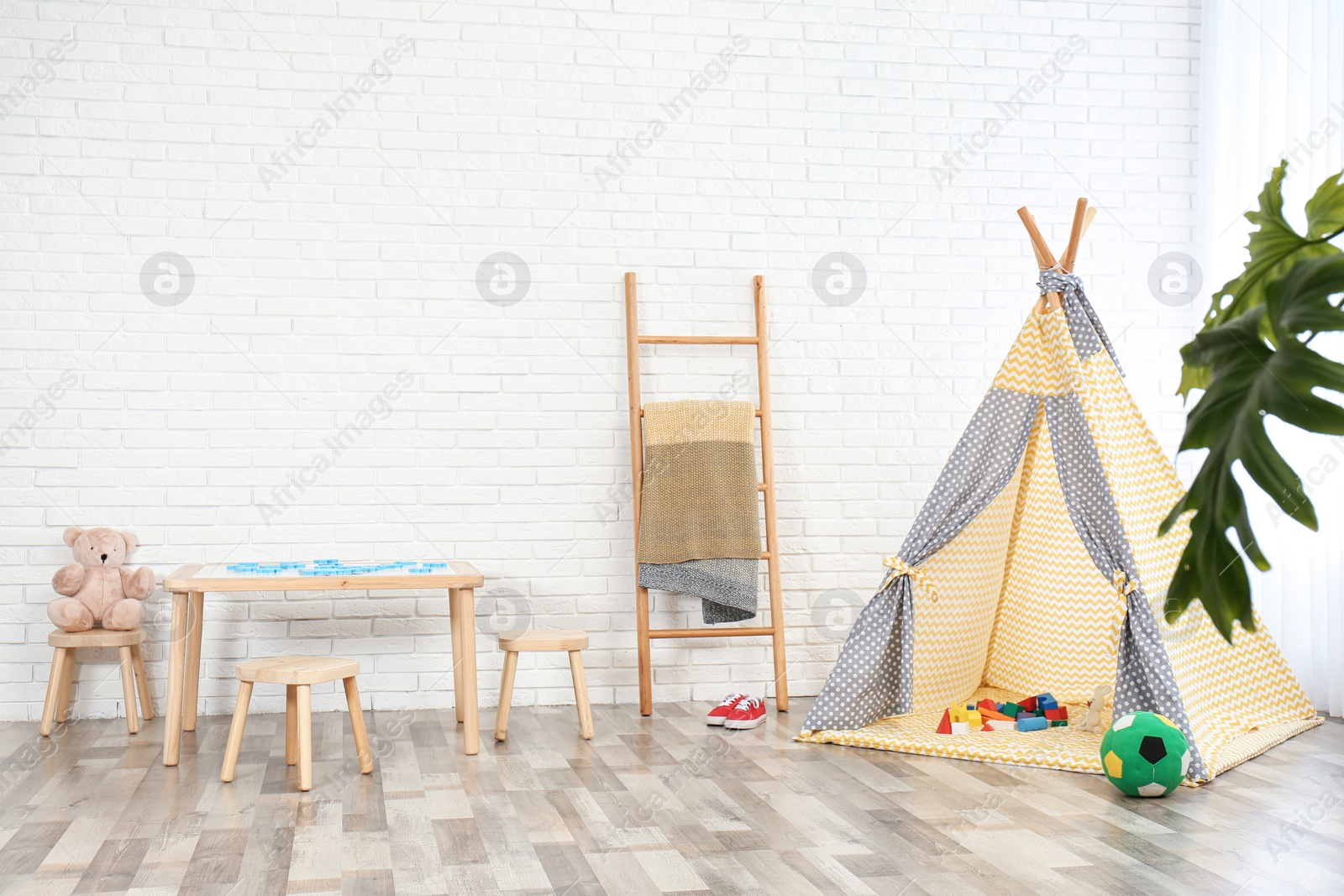 Photo of Cozy kids room interior with table, stools and play tent