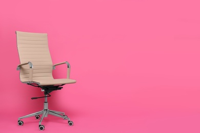 Photo of Comfortable office chair on pink background, space for text