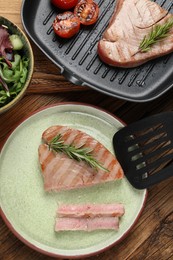Delicious tuna steaks with rosemary served on wooden table, flat lay