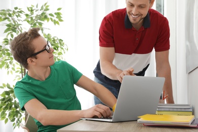 Photo of Father helping his teenager son with homework indoors