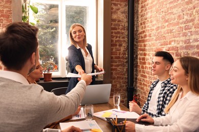 Photo of Businesswoman having meeting with her employees in office. Lady boss