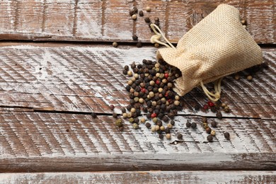 Photo of Aromatic spice. Different peppers in burlap bag on wooden table, top view. Space for text