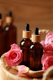Photo of Bottles of essential rose oil and flowers on tray