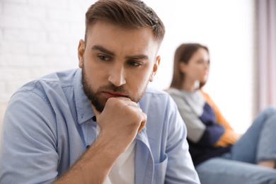 Photo of Unhappy couple with problems in relationship at home, focus on man