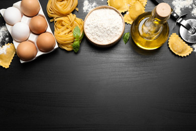 Photo of Flat lay composition with different types of pasta on black wooden table. Space for text