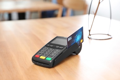 Photo of Credit card machine for non cash payment on wooden table indoors