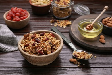 Photo of Tasty granola served with nuts and dry fruits on wooden table