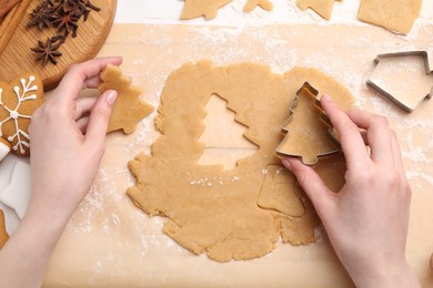 Photo of Woman making Christmas cookies with cutters at white table, top view