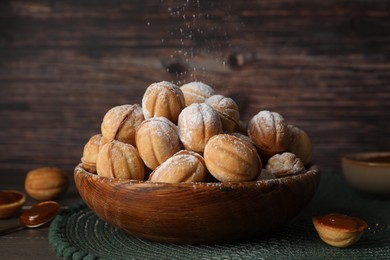 Photo of Bowl of delicious nut shaped cookies on wooden table