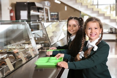 Photo of Children near serving line with healthy food in school canteen