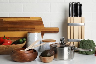 Photo of Different cooking utensils and fresh vegetables on countertop in kitchen