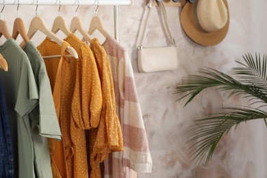 Different stylish clothes hanging on rack in room