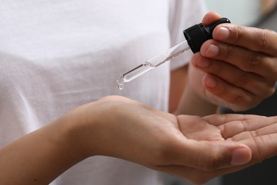 Photo of Woman applying cosmetic serum onto her hand, closeup