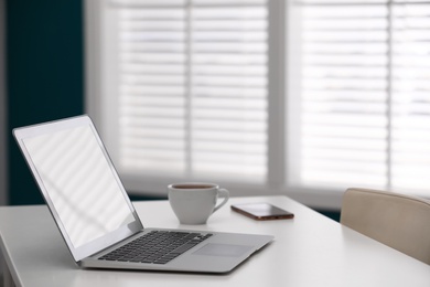 Photo of Comfortable workplace with modern laptop on desk in home office, space for text