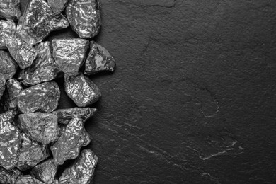 Photo of Pile of silver nuggets on black table, flat lay. Space for text