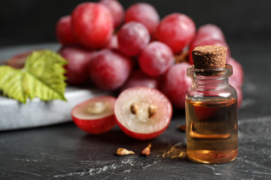 Photo of Bottle of natural grape seed oil on dark table. Organic cosmetic