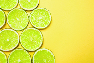 Photo of Juicy fresh lime slices on yellow background, flat lay. Space for text
