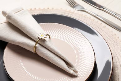 Photo of Plates with fabric napkin, decorative ring and cutlery on white wooden table