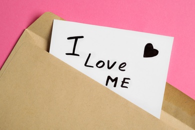 Photo of Paper note with phrase I Love Me in envelope on pink background, closeup