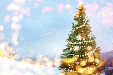 Image of Beautiful decorated Christmas tree outdoors, space for text. Bokeh effect