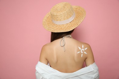 Photo of Teenage girl with sun protection cream on her back against pink background