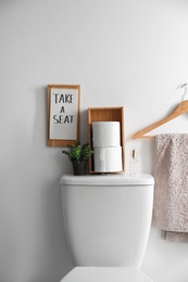 Decor elements, necessities and toilet bowl near white wall. Bathroom interior