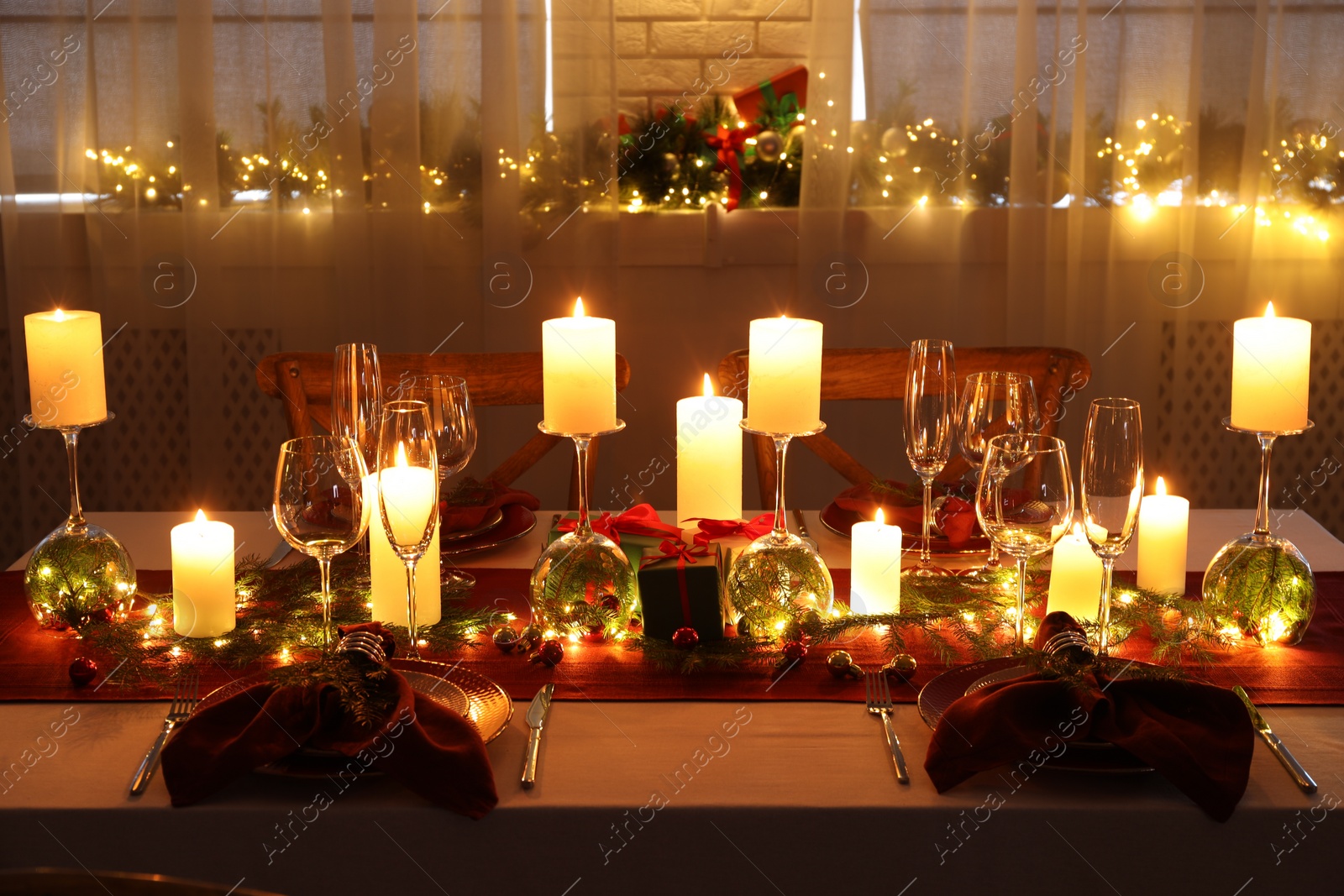 Photo of Christmas table setting with burning candles and festive decor