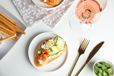 Delicious bruschetta with shrimps served on white table, flat lay