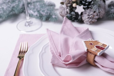 Photo of Plates and pink fabric napkin with beautiful decorative ring on white table. Space for text
