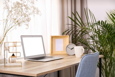 Photo of Stylish workplace interior with laptop on wooden table near window