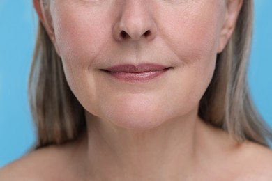 Photo of Senior woman with aging skin on light blue background, closeup. Rejuvenation treatment
