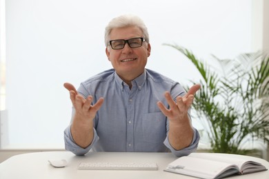 Photo of Mature man using video chat in office, view from web camera