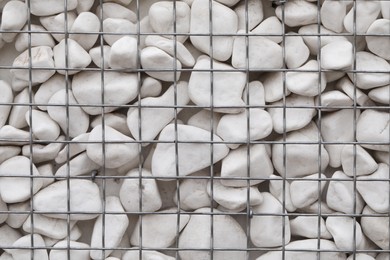 Photo of Beautiful white stones inside metal mesh as background