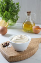 Photo of Tasty mayonnaise sauce in bowl, spices and ingredients on white table, closeup