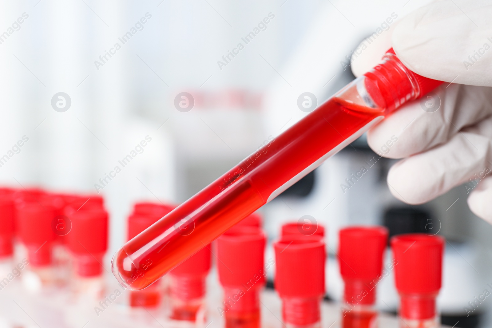 Photo of Scientist holding test tube with blood sample in laboratory, closeup. Virus research