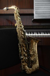 Photo of Beautiful saxophone near grand piano. Musical instruments