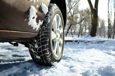 Car with winter tires on snowy road, closeup view. Space for text