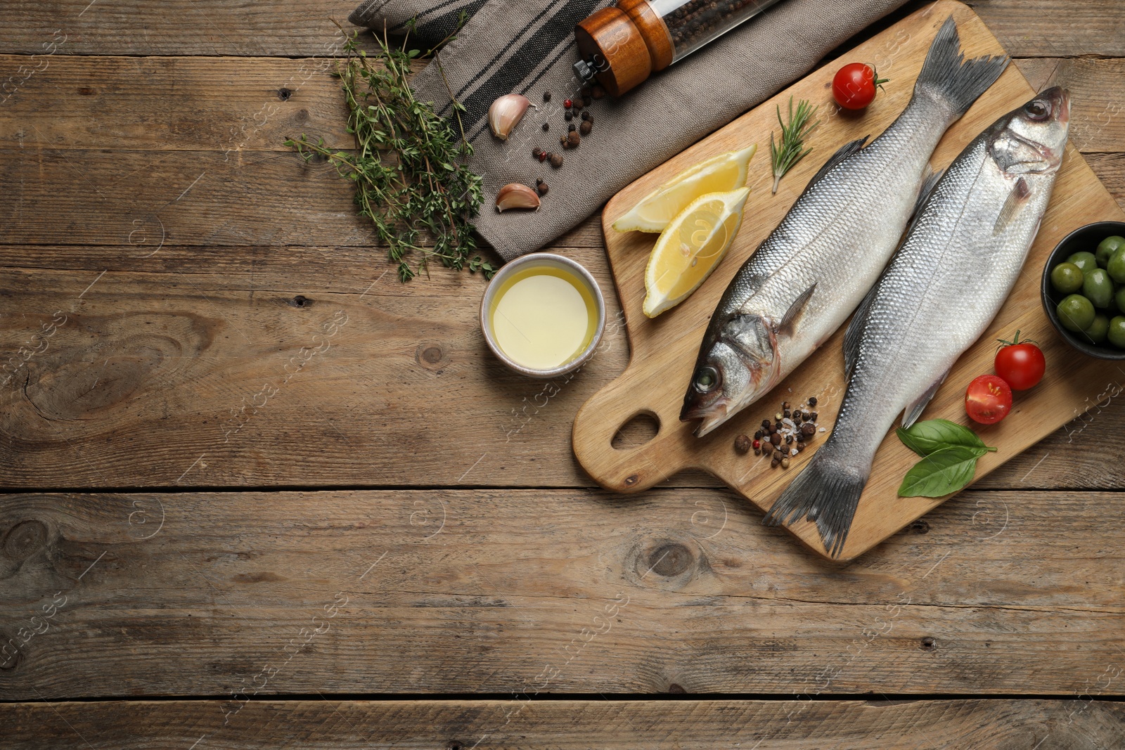 Photo of Sea bass fish and ingredients on wooden table, flat lay. Space for text