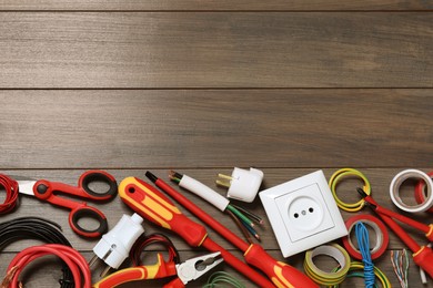 Photo of Set of electrician's tools and accessories on wooden table, flat lay. Space for text