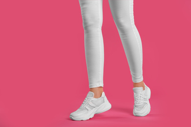 Photo of Woman wearing sneakers on pink background, closeup