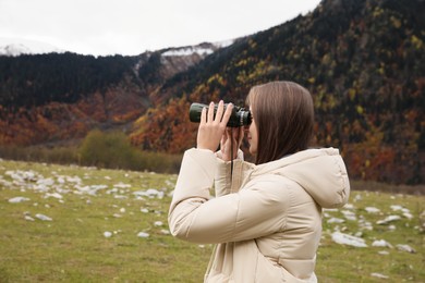 Photo of Woman looking through binoculars in beautiful mountains. Space for text