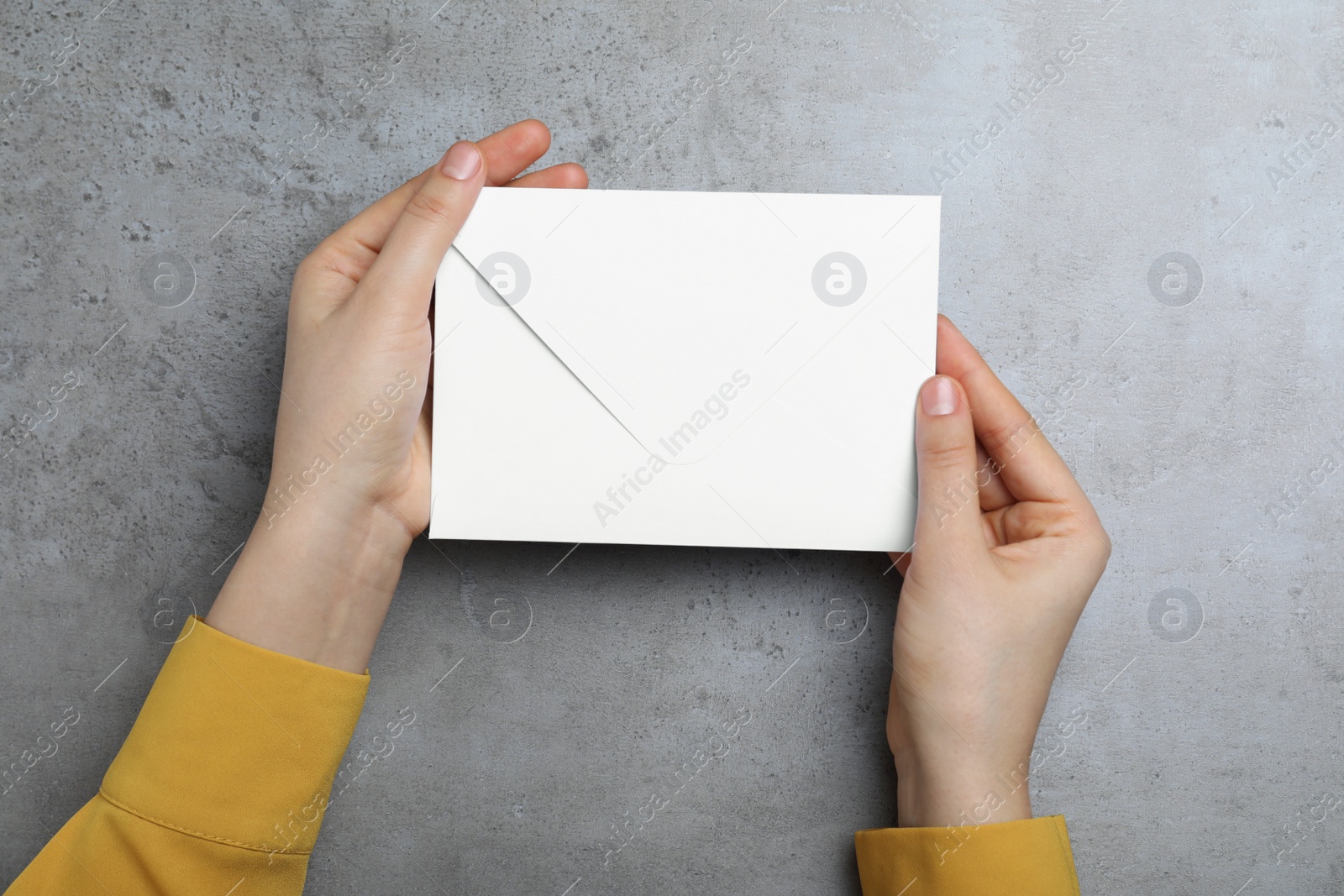 Photo of Woman with envelope at grey table, top view